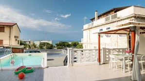 Poolområde på taget med havudsigt, et spiseområde med udendørs møbler og solsenge ved poolen.