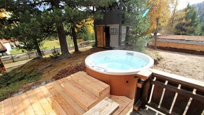 A hot tub on a wooden deck with a wooden fence and trees in the background. - Sunlit Cabin With Jacuzzi in Turracherhohe (Stadl-Predlitz)