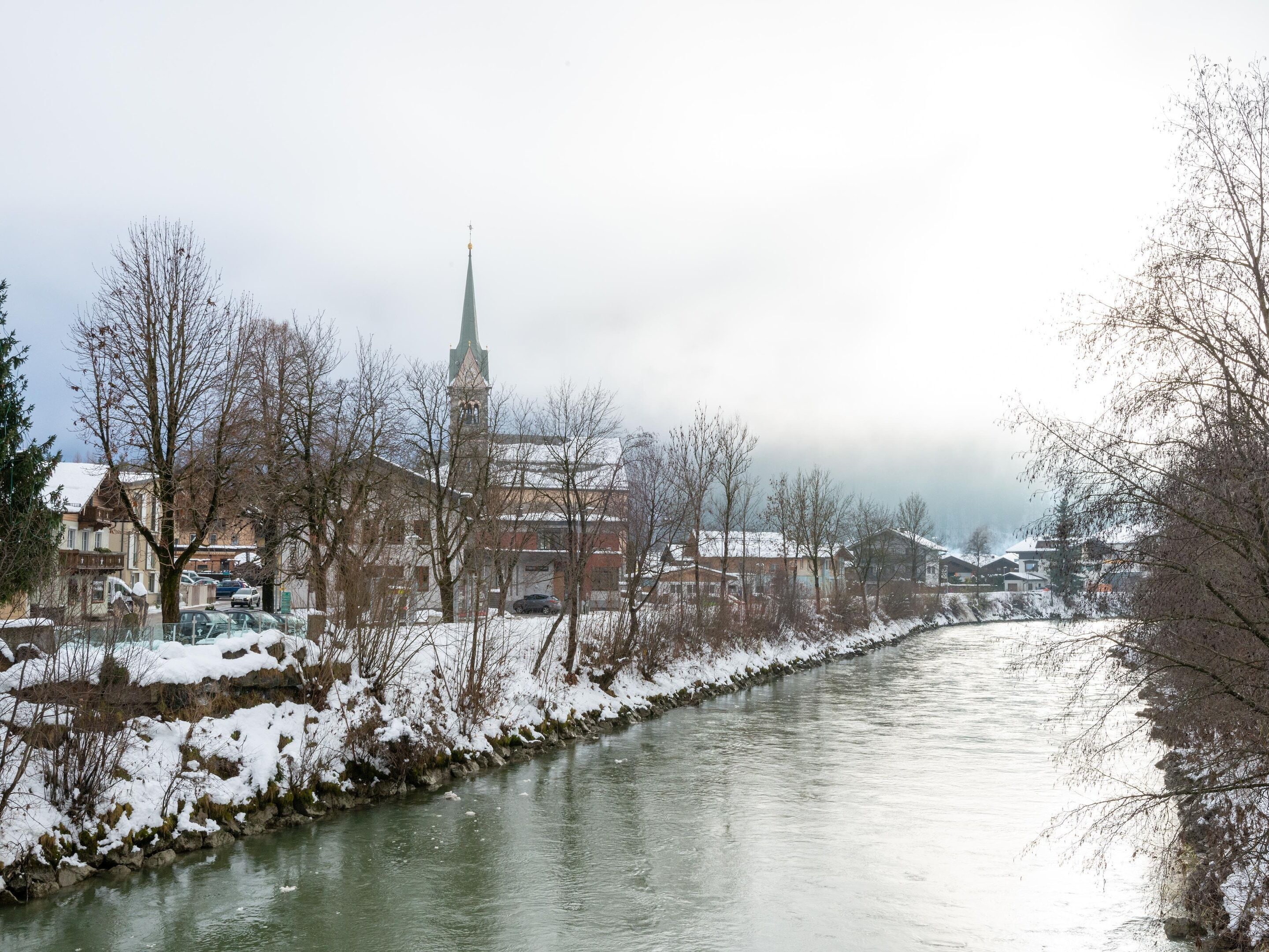 A river with snow-covered banks and buildings in the background.