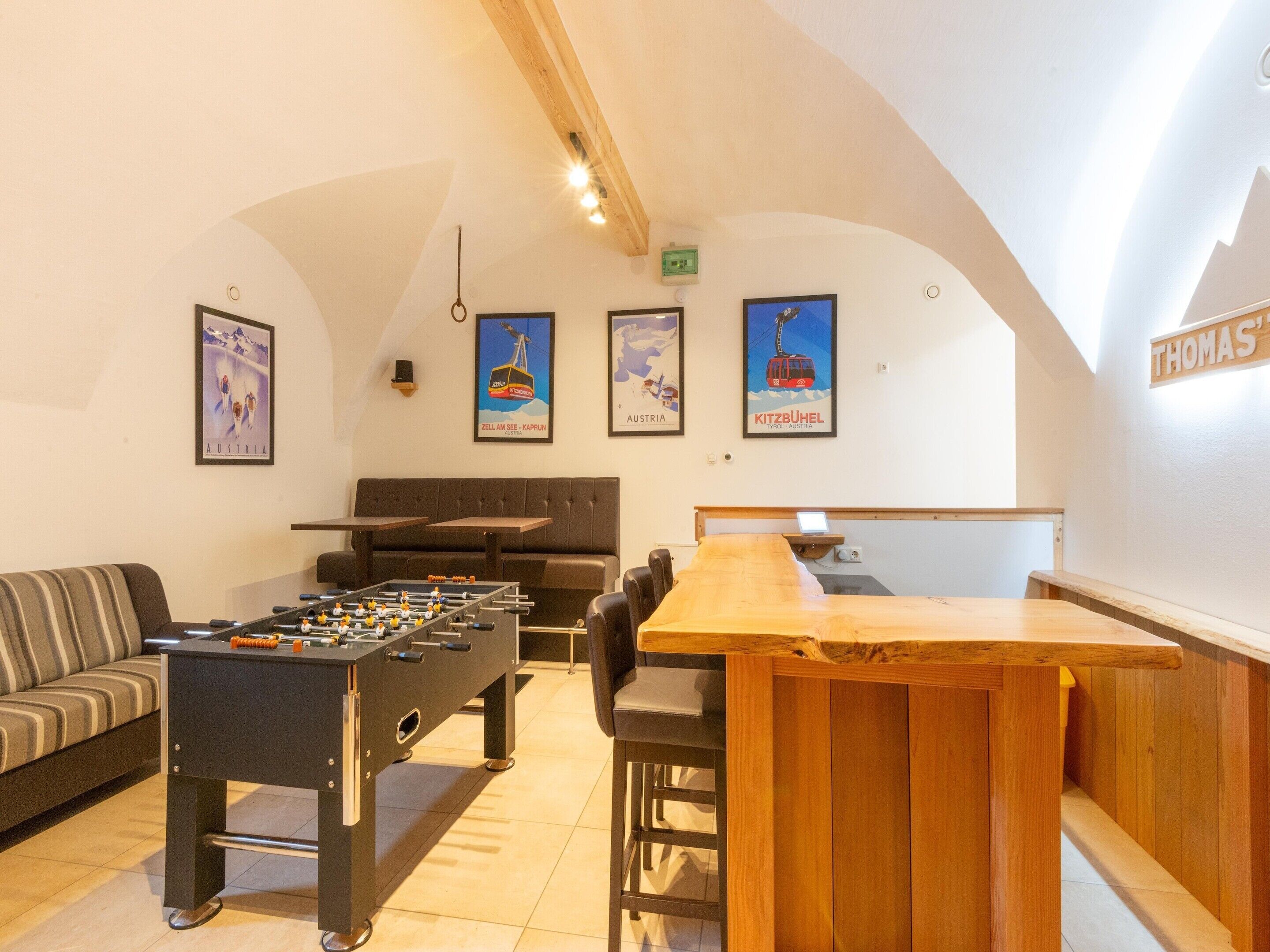A cozy lounge area with a foosball table, a sofa, and a wooden bar.