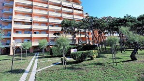 A multi-story hotel with balconies, a central courtyard with trees, and a clear sky. - Nice Apartment in Porto Santa Margherita With Terrace (Caorle)