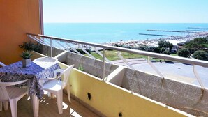 A balcony with a table and chairs, overlooking a beach and the sea. - Nice Apartment in Porto Santa Margherita With Terrace (Caorle)
