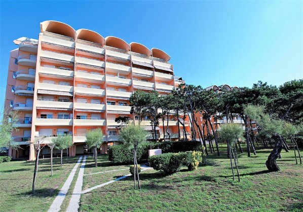 Un hôtel à plusieurs étages doté de balcons, d’un jardin arboré et offrant une vue sur un ciel dégagé.