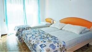 A bedroom with two beds, a large window with sheer curtains, and a painting on the wall. - Nice Apartment in Porto Santa Margherita With Terrace (Caorle)