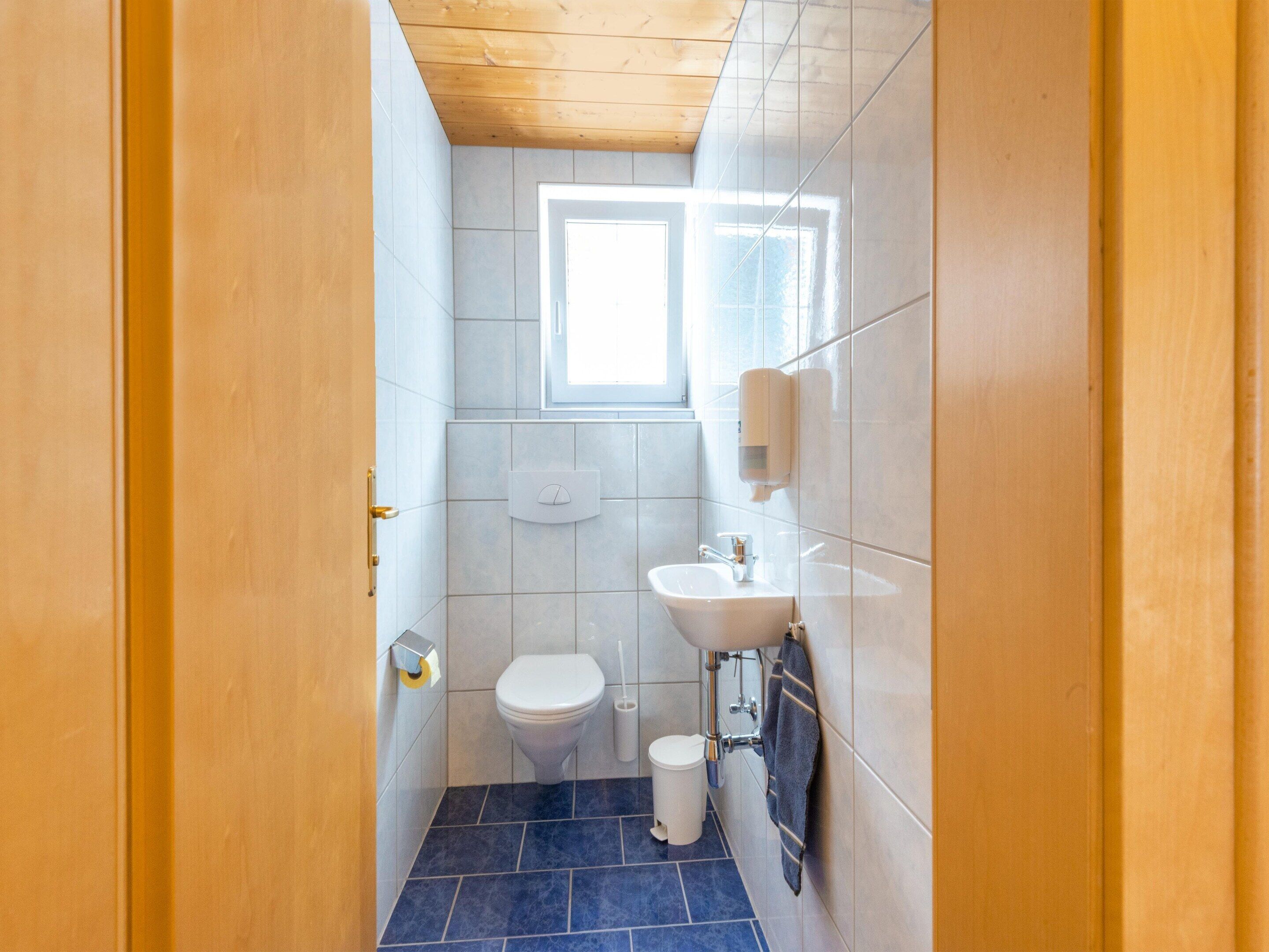 Un baño pequeño con inodoro, lavamanos y ventana.