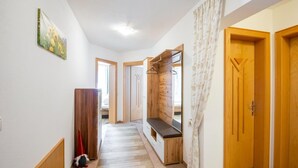 Un pasillo con puertas de madera, un banco y una pequeña mesa.