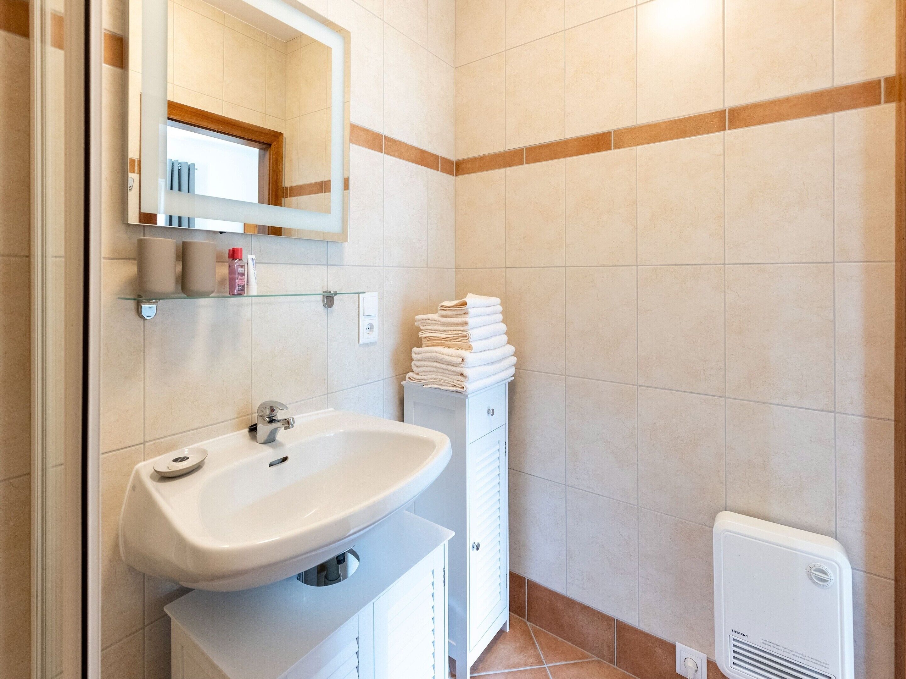A bathroom with a white sink, a mirror, a towel rack, and a radiator.