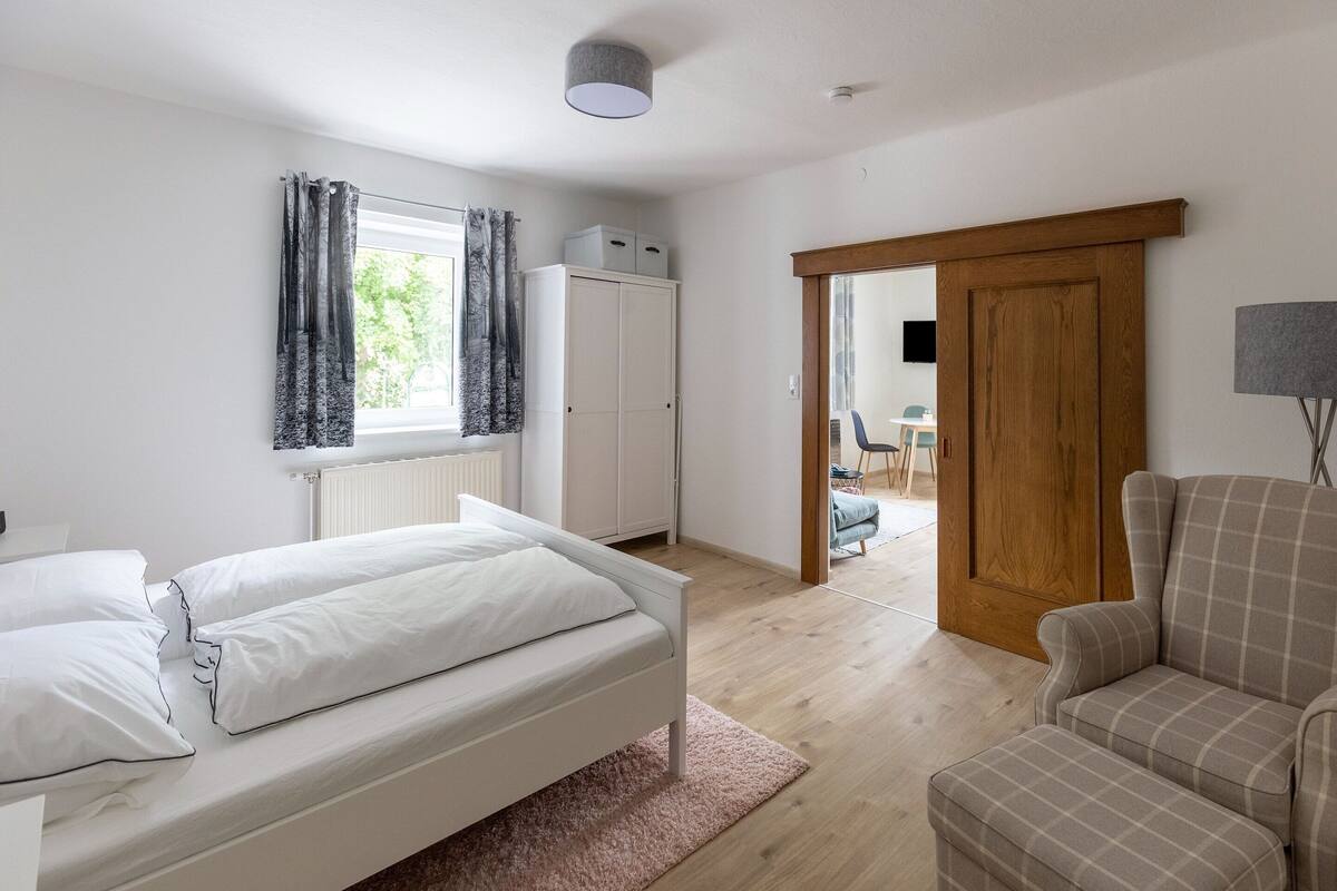 Une chambre à coucher avec un lit, une armoire en bois, un bureau et une chaise.
