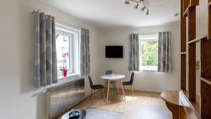 Ein modernes Zimmer mit Esstisch, Stühlen, Fernseher und Heizkörper.
