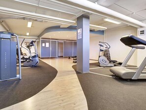 Ein Fitnessraum mit Cardiogeräten, Gewichtstrainern und Holzboden.