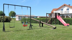 A playground with swings, a slide, and a climbing structure. - Ruhiges Appartement in Strandnaehe in Wohlenberg, Deutschland (Klütz)