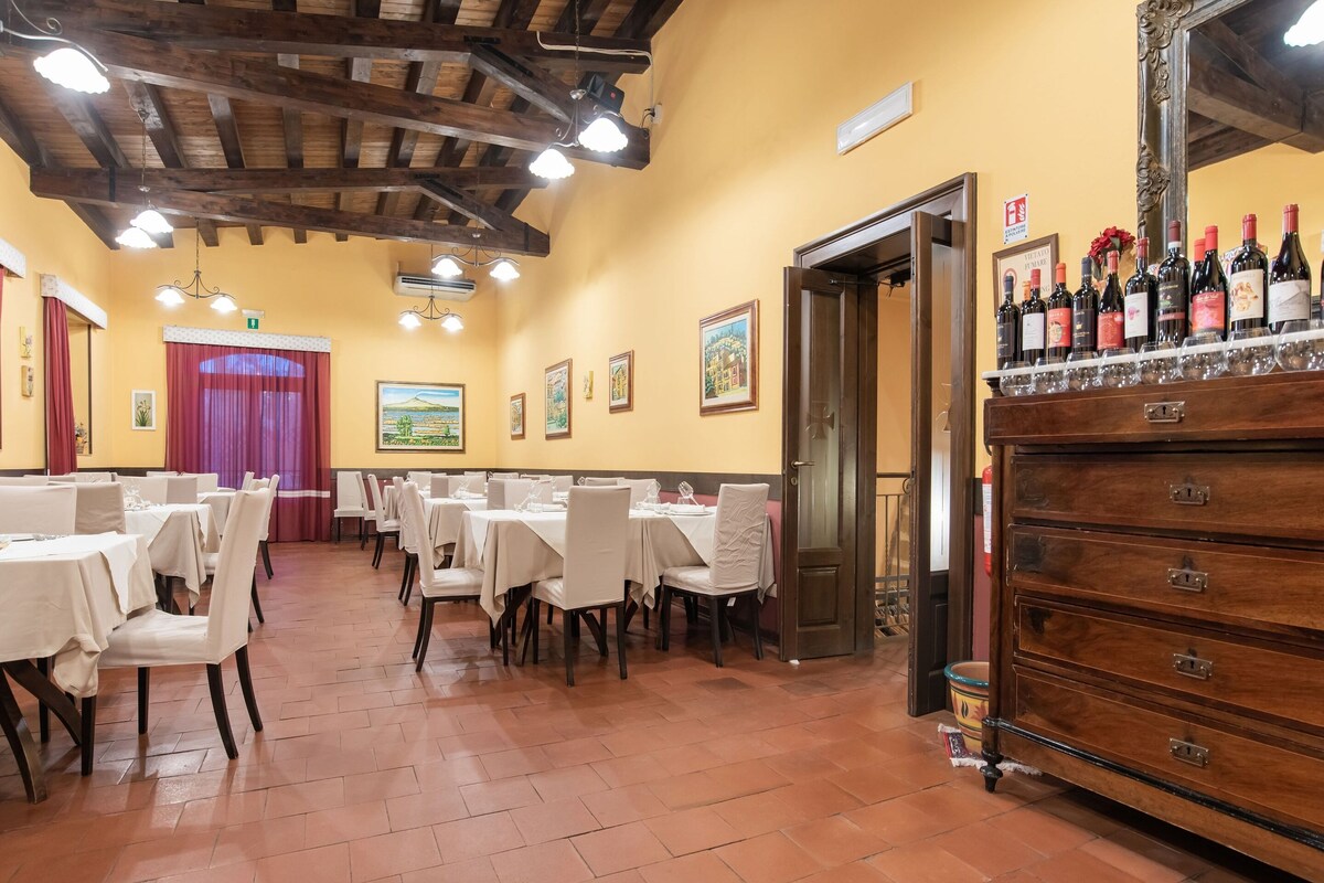 A dining area with multiple tables and chairs, a wooden ceiling, and a wine display.