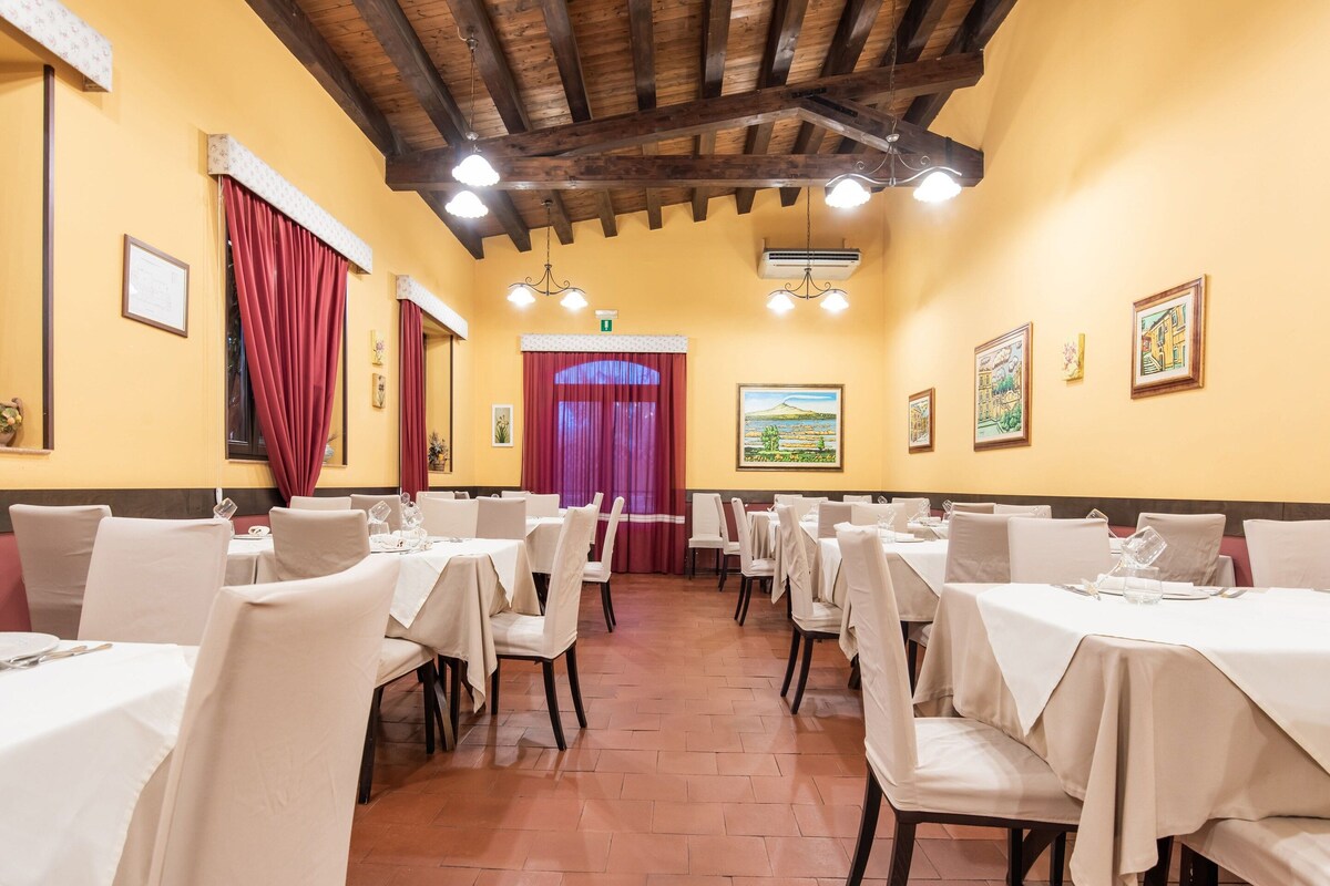 A restaurant with multiple tables, red curtains, and a painting on the wall.