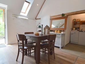 A dining area with a wooden table and chairs, a kitchen with a sink and cabinets, and a skylight above.