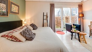 Une chambre avec un grand lit, une chaise, une petite table et une vue sur l’extérieur.