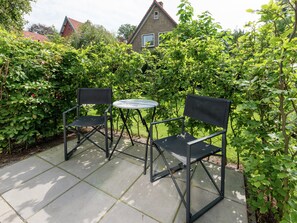 An outdoor patio with two black metal chairs and a small round table. - Alluring Apartment in Bergen With Terrace, Garden and BBQ (Bergen)