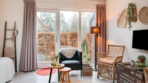 Un salon confortable avec un canapé, des fauteuils, une petite table et un téléviseur.