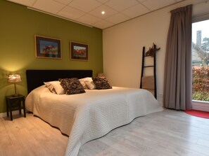 A bedroom with a large bed, green walls, and two framed pictures on the wall. - Alluring Apartment in Bergen With Terrace, Garden and BBQ (Bergen)