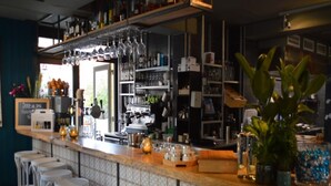 Un espace bar avec des tabourets, des étagères remplies de bouteilles et un menu écrit à la craie.