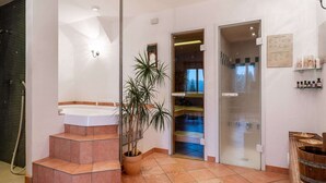 Uma casa de banho moderna com banheira, chuveiro e lavatório. Escadas levam a um espaço de estar pequeno com uma planta.
