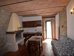 A cozy interior with a stone fireplace, wooden dining table, and a patterned sofa. - Cozy Holiday Home in Modigliana Italy With Garden (Modigliana)