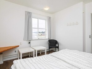 Simple, functional room with a single bed, small table, and wicker chair.