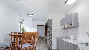 Une cuisine compacte avec un coin repas, une arche en pierre et des appareils électroménagers modernes.