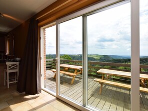 Ein Balkon mit Holztischen und Blick ins Grüne.