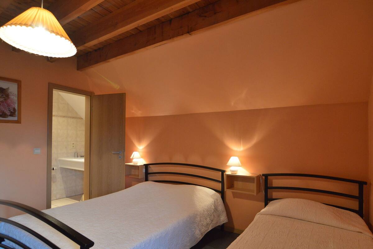 A bedroom with two beds, wooden headboards, and bedside lamps.