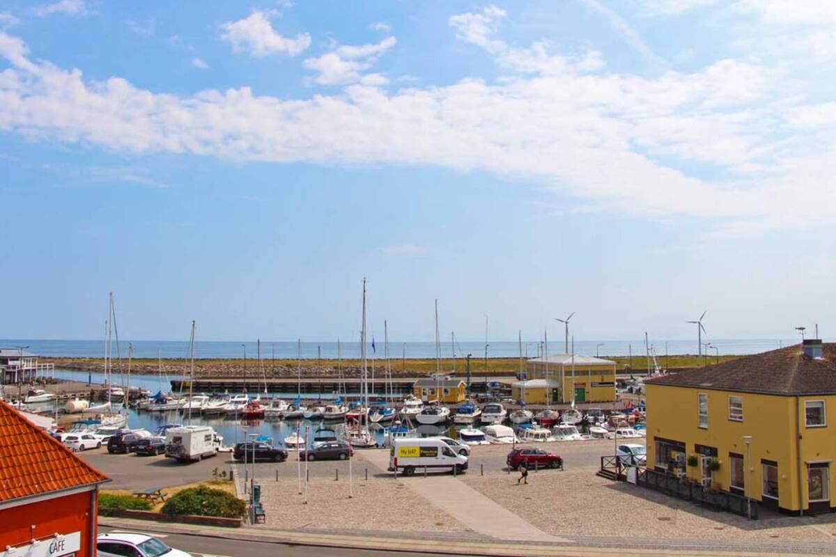 Un port de plaisance avec des bateaux, un café et un bâtiment jaune.