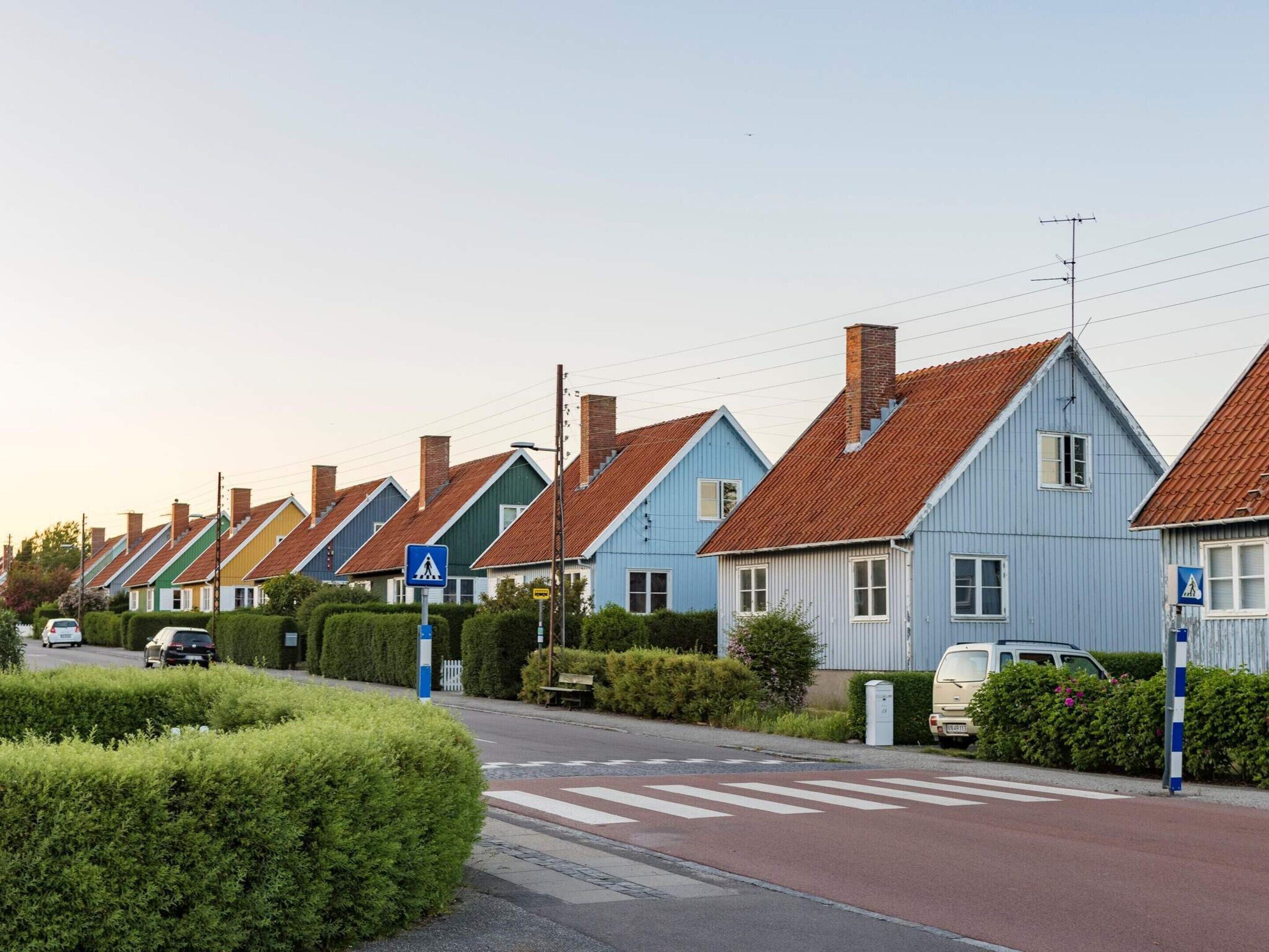 A row of uniform houses with a pedestrian crossing and a clear road.