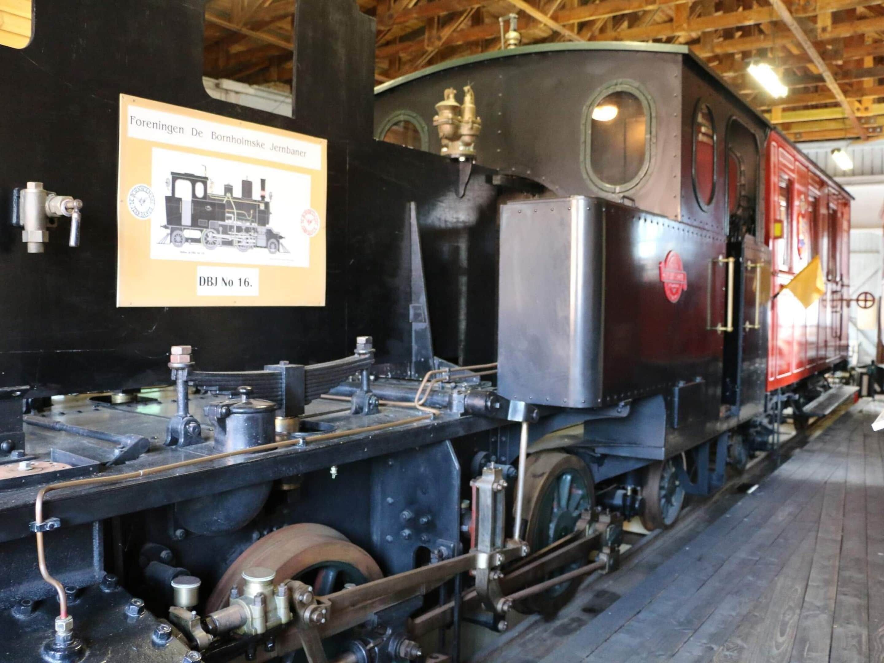 A steam locomotive with visible mechanical components and a signboard.
