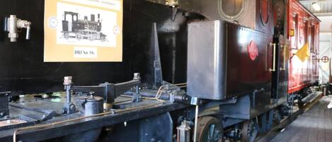A steam locomotive with visible mechanical components and a signboard.