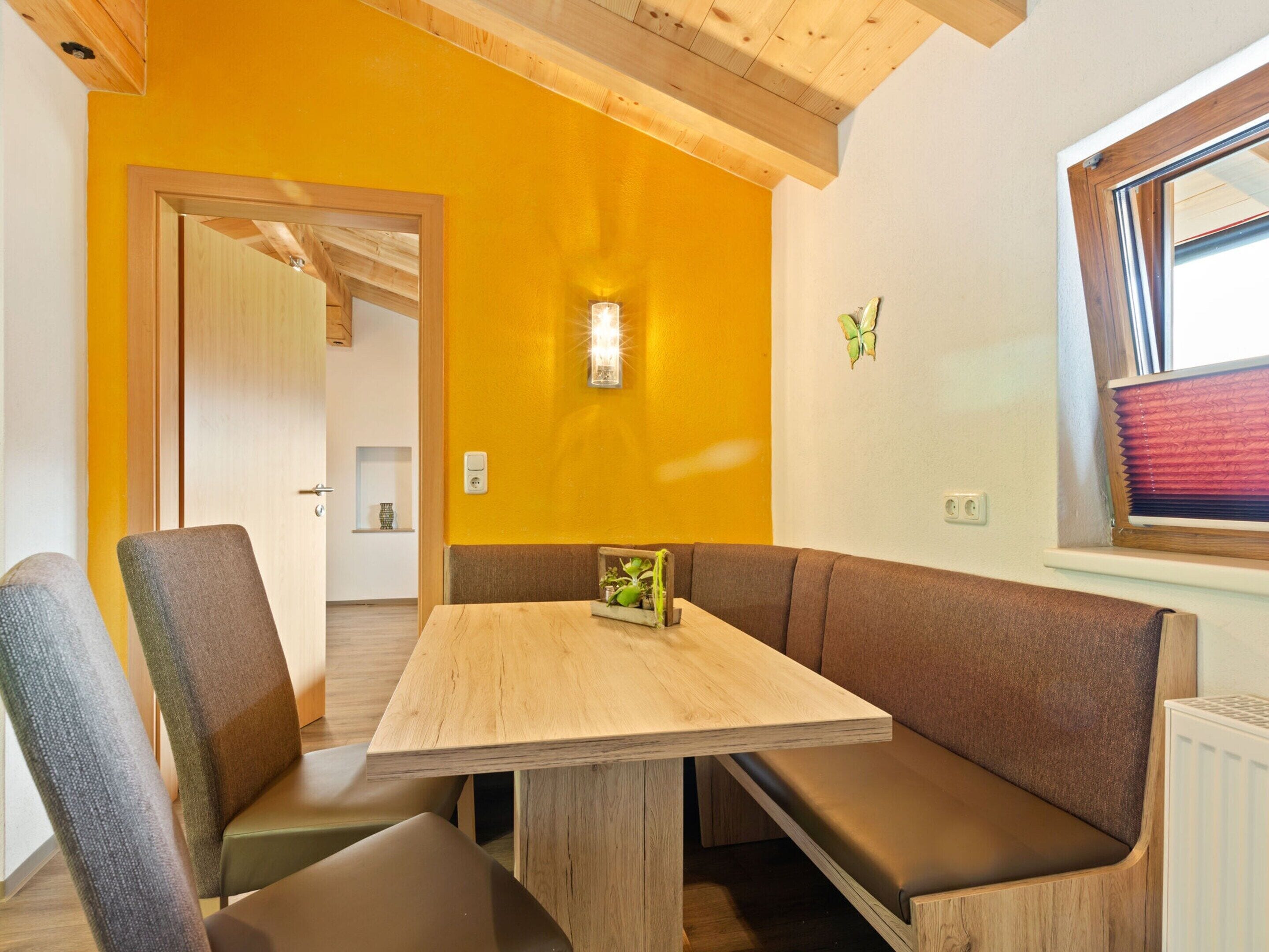 Een eetruimte met een houten tafel en bruine bekleden bankjes.