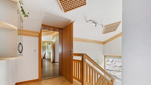 A spacious hallway with a wooden staircase, a door leading to another room, and a view of the outdoors. - Sunlit Apartment Near Ski Area in Hollersbach im Pinzgau (Hollersbach im Pinzgau)