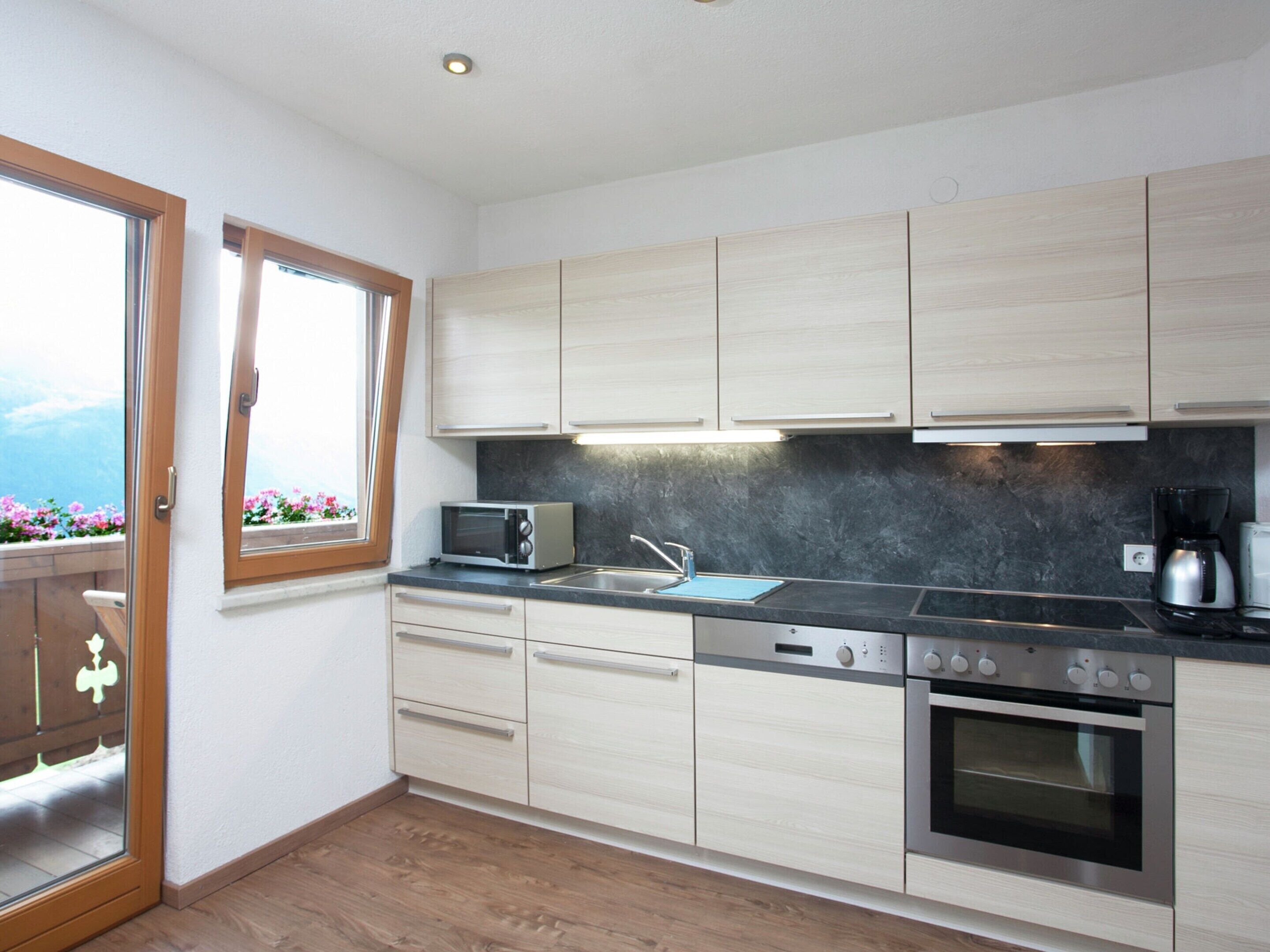 A modern kitchen with light wood cabinets, a microwave, a stove, and a coffee maker.