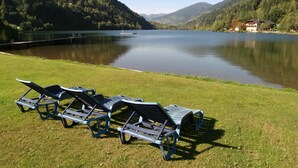 Une vue sur le lac, avec des chaises longues et un bâtiment en arrière-plan.
