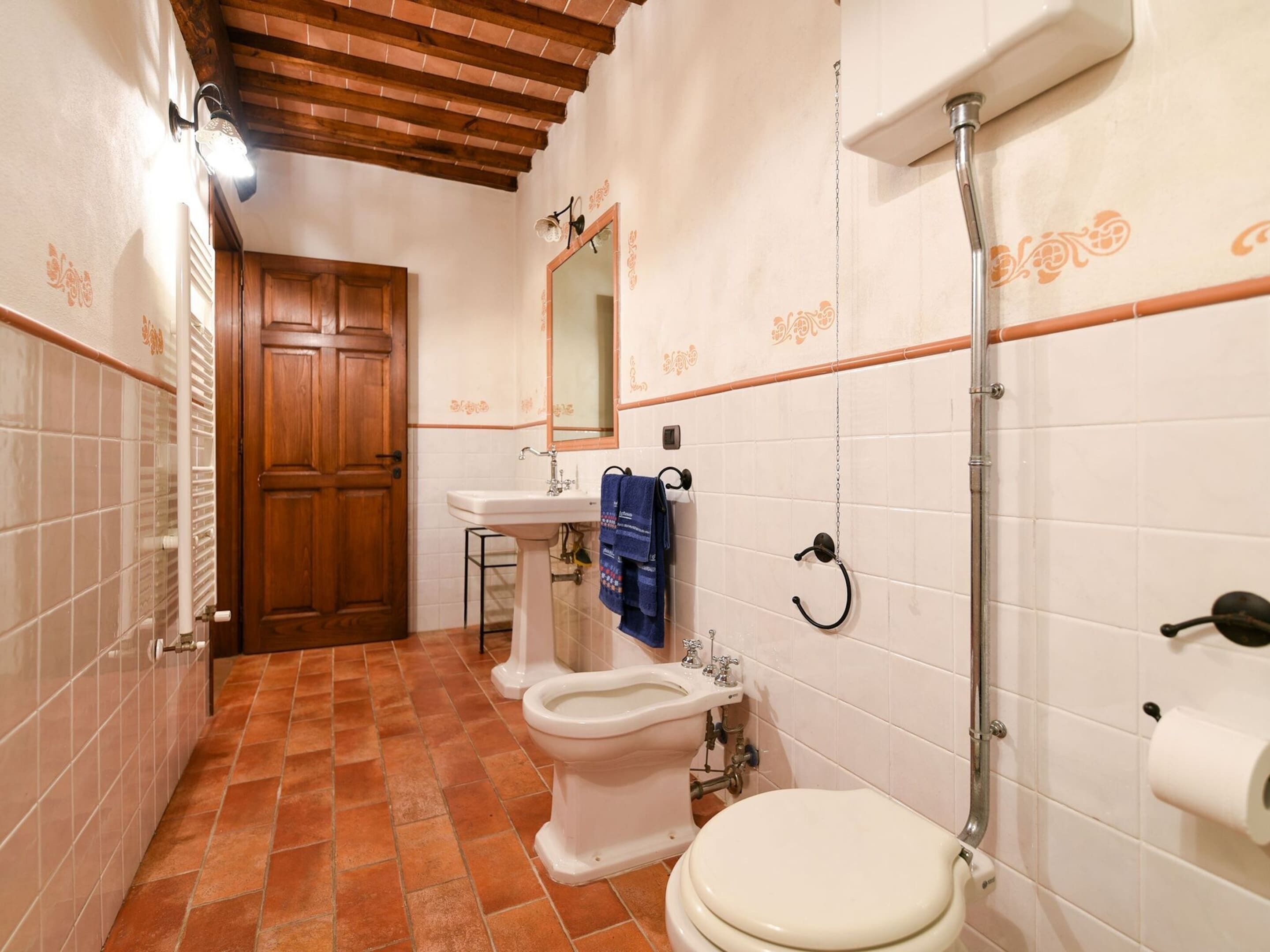 A bathroom with a wooden door, a sink, a toilet, and a shower.