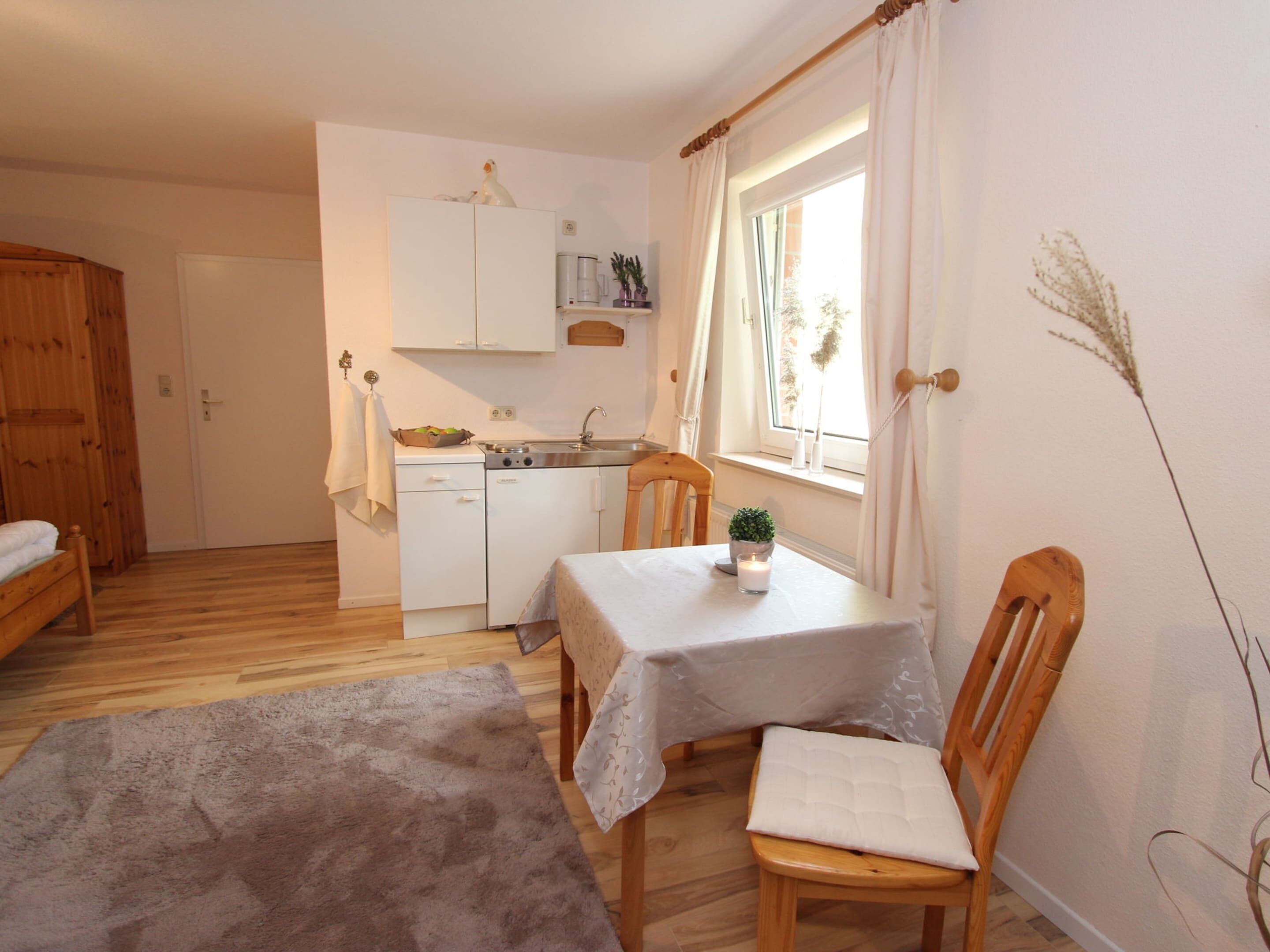 A compact kitchen with a dining area, wooden furniture, and a window with curtains.