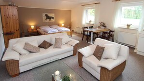 A cozy room with a bed, two sofas, a dining table, and a window. - Holiday Home in Kirchdorf With Swimming Pool,terrace, Garden (Kirchdorf)