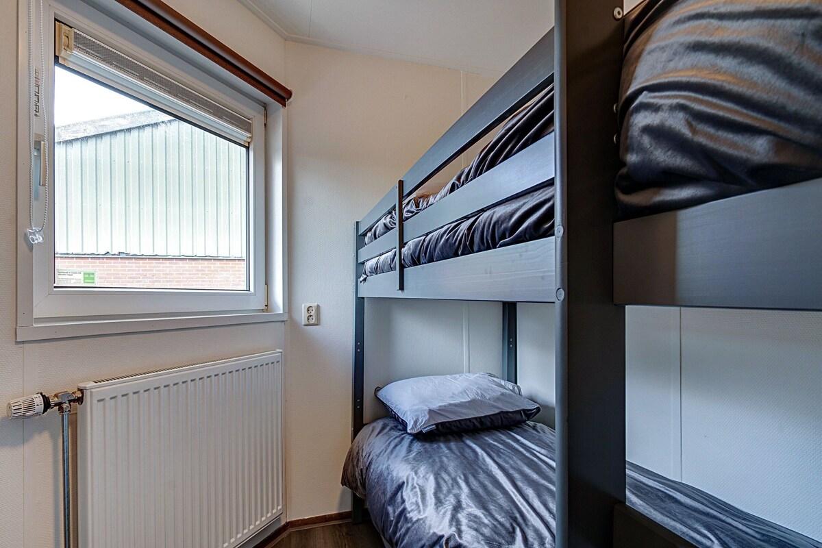 A bunk bed room with a window, radiator, and wooden floor.