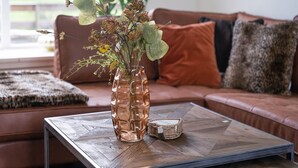 A living room with a coffee table, a vase with flowers, and a couch with cushions. - Secluded Chalet in Suwald With Hottub (Suwâld)
