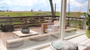 A patio with outdoor seating, a large planter with flowers, and a view of a rural landscape. - Secluded Chalet in Suwald With Hottub (Suwâld)
