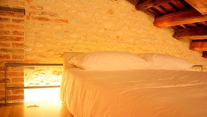 A bedroom with a brick wall, a wooden ceiling, and a bed with white bedding. - Modern Farmhouse in Pagnano Italy Near Forest (Asolo)