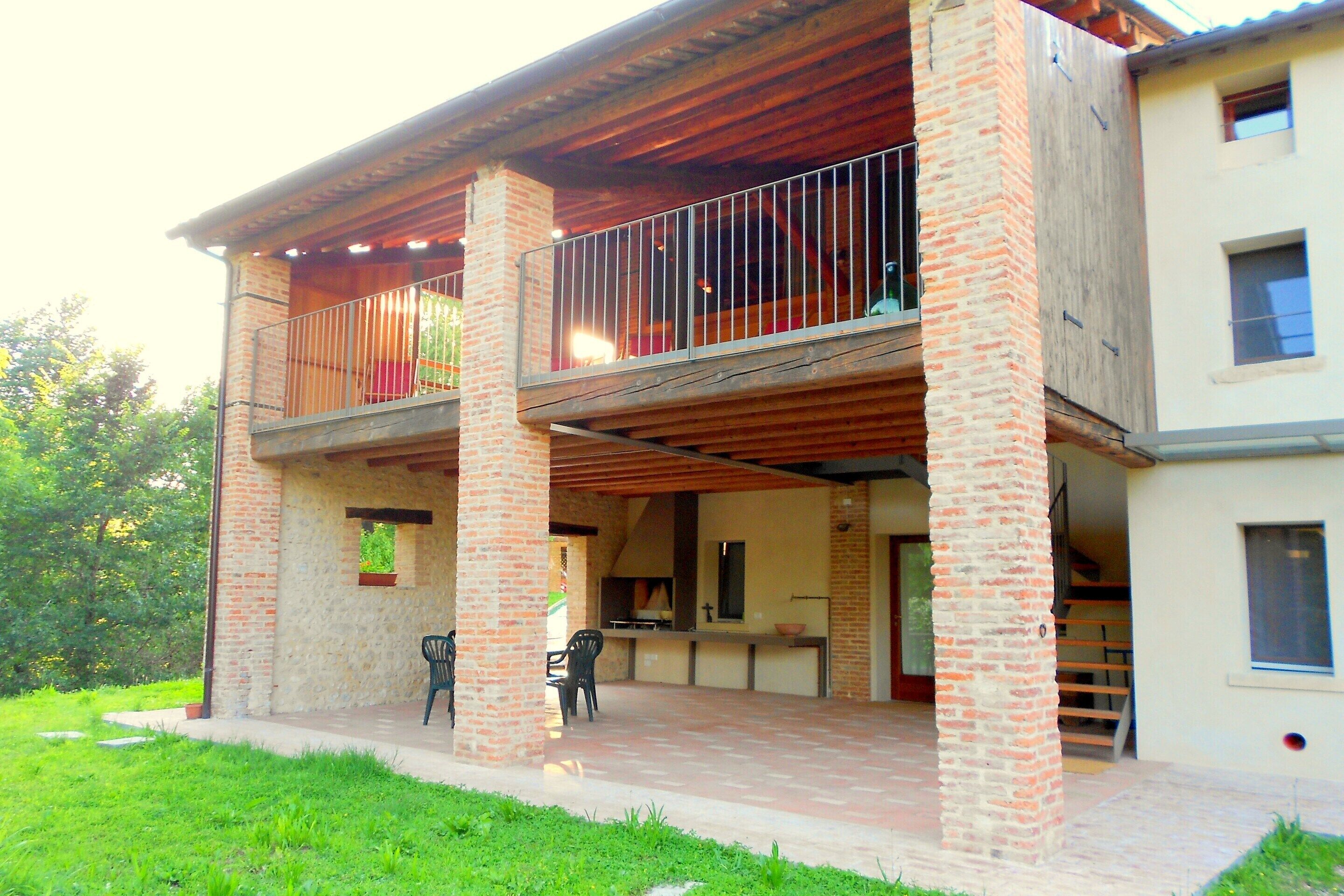 Un bâtiment à deux étages doté d’un balcon, de colonnes en briques et d’un patio couvert.