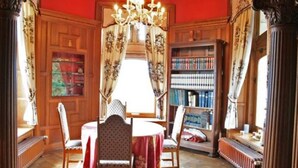 A room with a wooden paneled wall, a chandelier, a round table with chairs, and a bookshelf. - Live Your Dream at This Castle in the City of Spa (Jalhay)