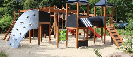 A playground with a slide, climbing structures, and a sandpit.