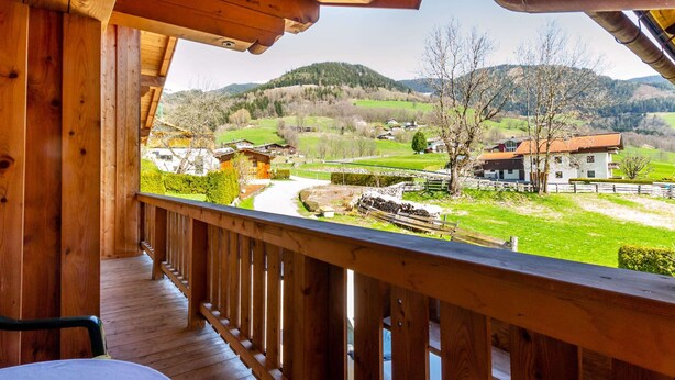 A wooden balcony with a view of a rural landscape, including houses and mountains. - Special Apartment in Walchen With Private Terrace (Piesendorf)