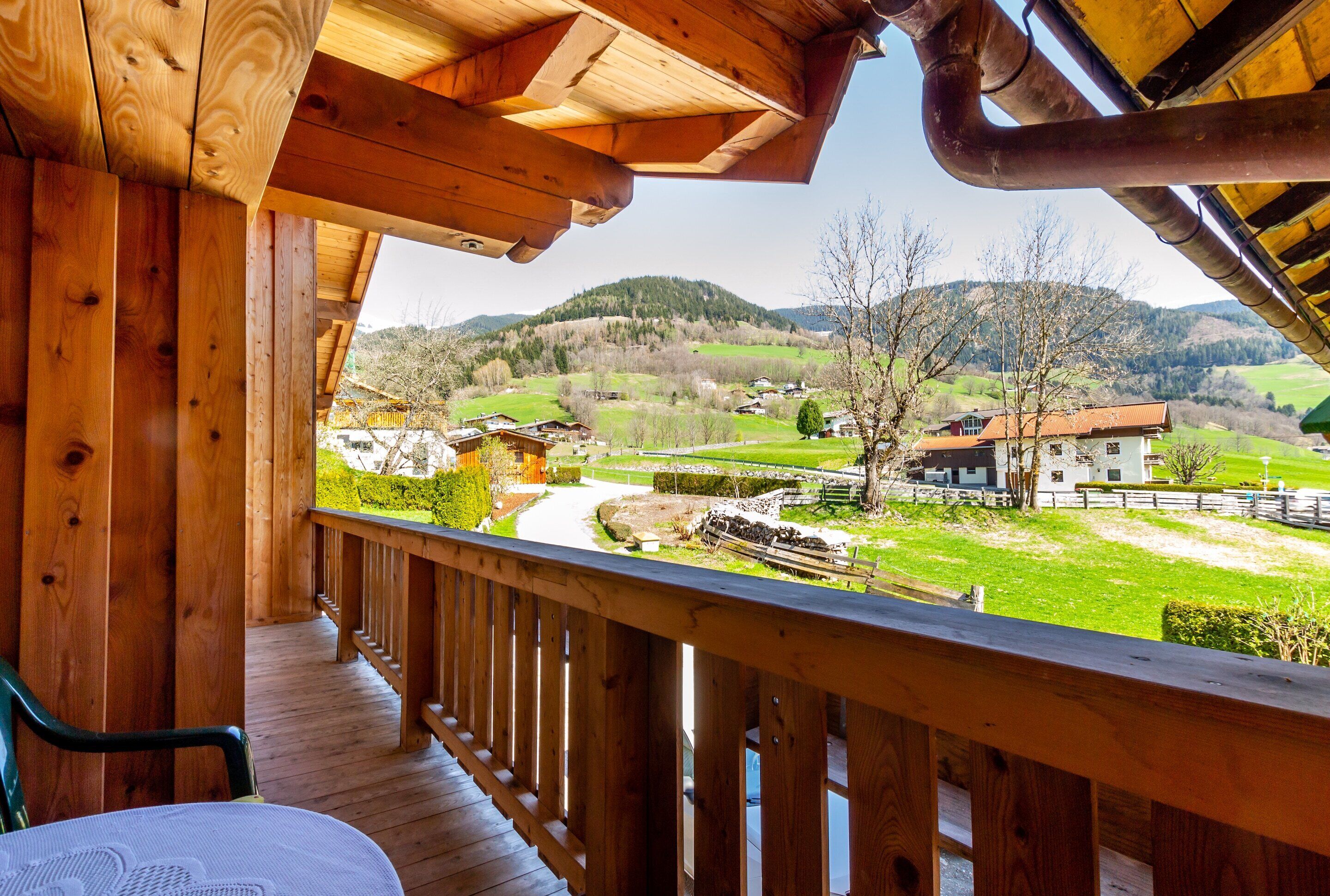 A wooden deck with a view of a rural landscape, including houses and hills.