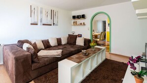 A modern living room with a brown sofa, a white coffee table, and a green archway leading to a dining area. - Special Apartment in Walchen With Private Terrace (Piesendorf)